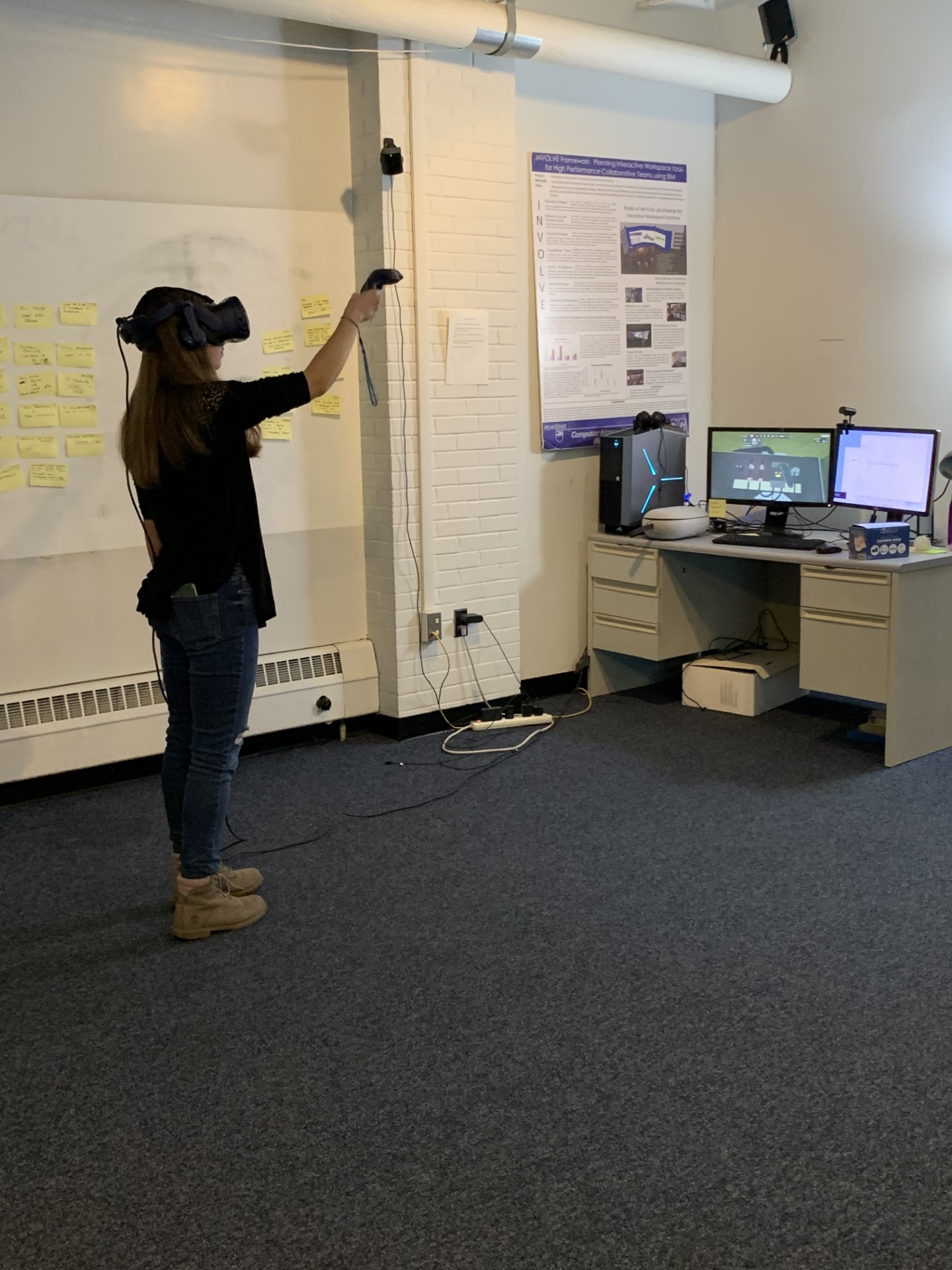 Research participant using a virtual reality headset and controllers in an immersive-experience lab.